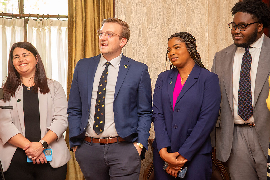 Four individuals standing in a row speaking at an event